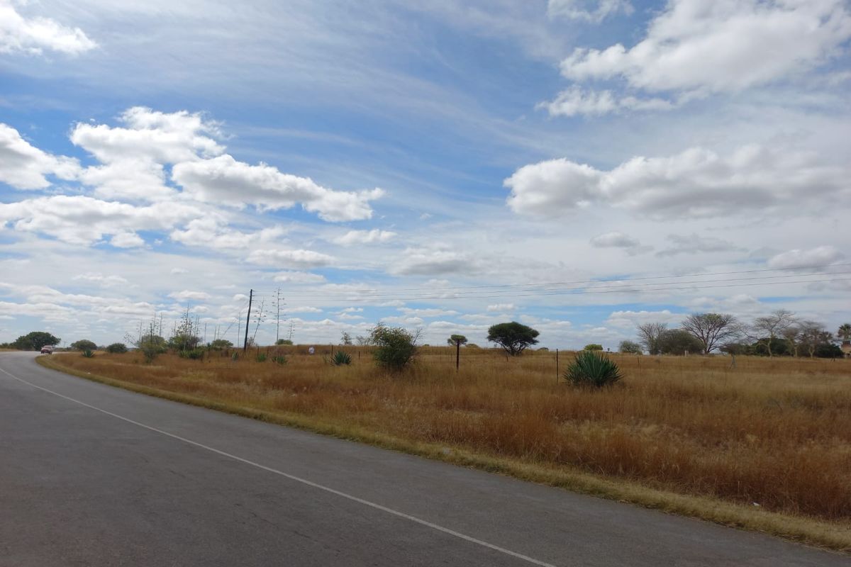 A view of the open farm landscape and surrounding terrain from the adjacent paved road.