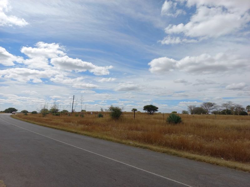A view of the open farm landscape and surrounding terrain from the adjacent paved road.