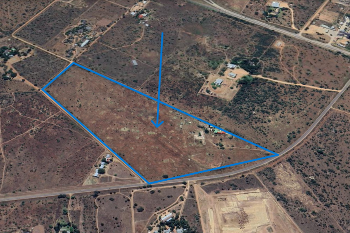 An aerial view of a large, undeveloped farm plot with clear boundary markings and surrounding rural landscape.