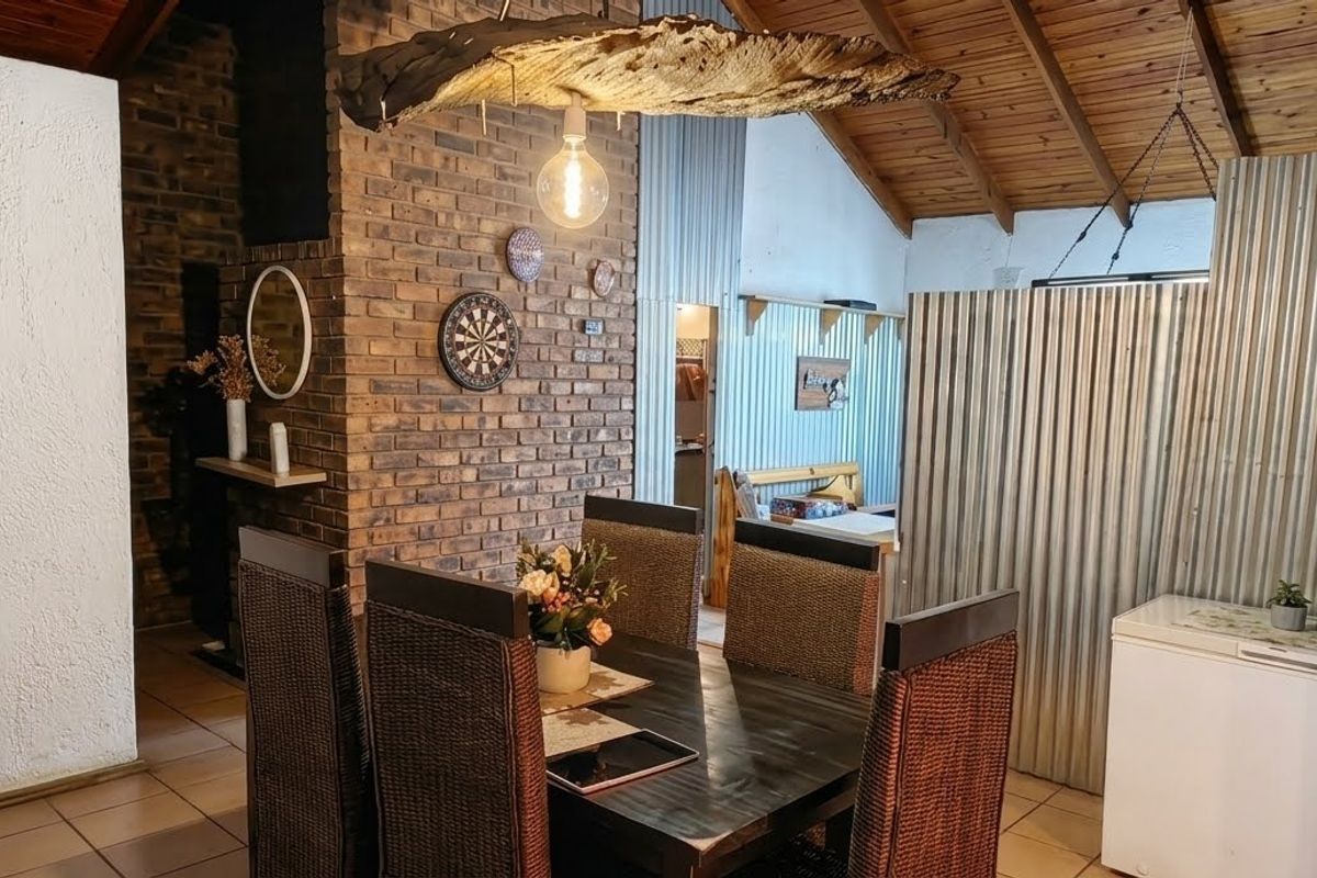 A rustic living area featuring exposed brickwork, a high timber raked ceiling, and corrugated metal wall accents, creating a unique industrial-style interior space.