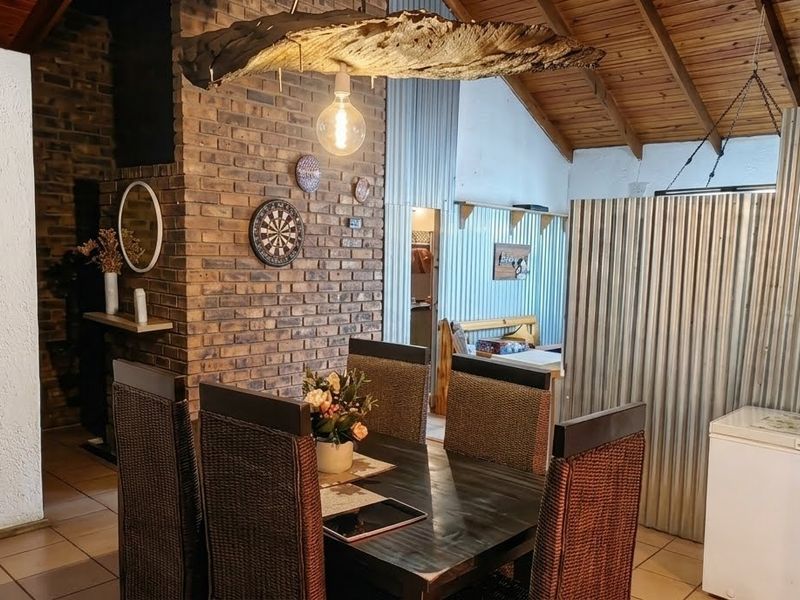 A rustic living area featuring exposed brickwork, a high timber raked ceiling, and corrugated metal wall accents, creating a unique industrial-style interior space.