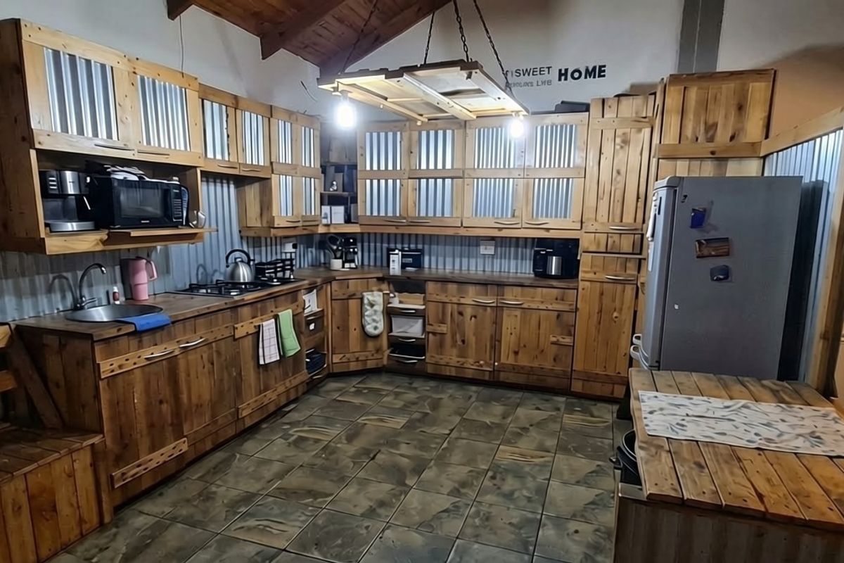 Rustic-style kitchen featuring timber cabinetry, corrugated metal splashbacks, tiled flooring, and exposed timber ceiling beams with integrated lighting.