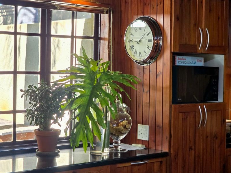 A kitchen area featuring timber-paneled walls, dark stone countertops, and a built-in microwave housing unit.