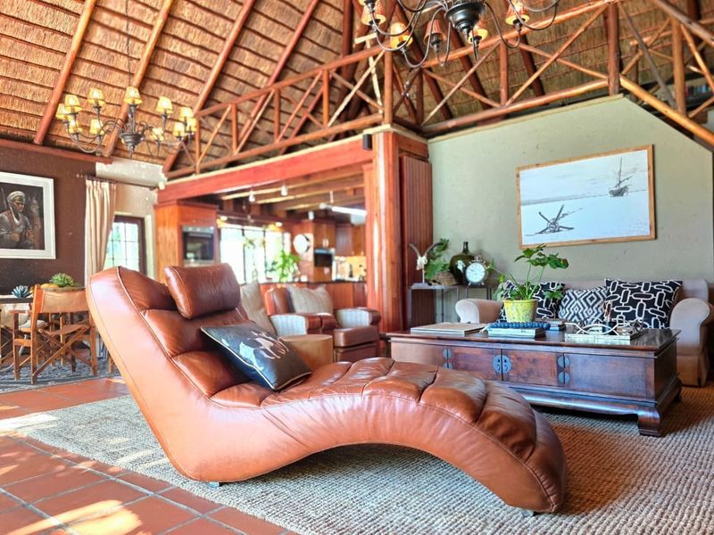 Spacious open-plan living area featuring a high vaulted thatched roof, exposed timber trusses, and terracotta floor tiles, creating a warm and rustic atmosphere.