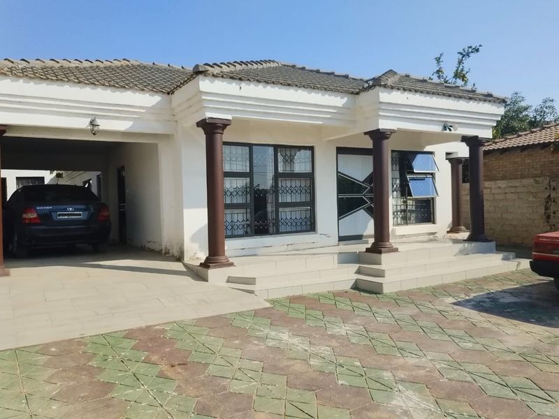 Front elevation of a single-story house featuring a covered carport, tiled entrance steps, decorative columns, and security bars on windows.