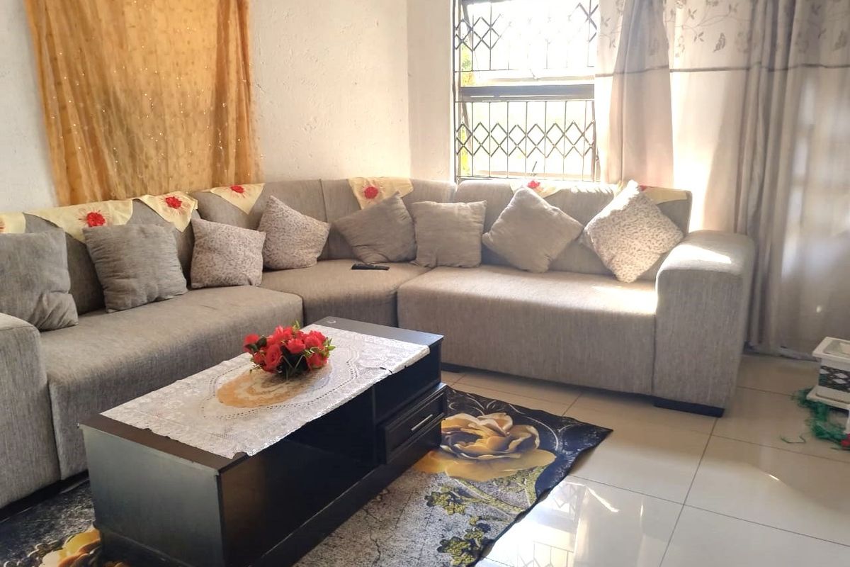 A living room featuring tiled flooring and a security gate on the window, providing a functional and secure living space.