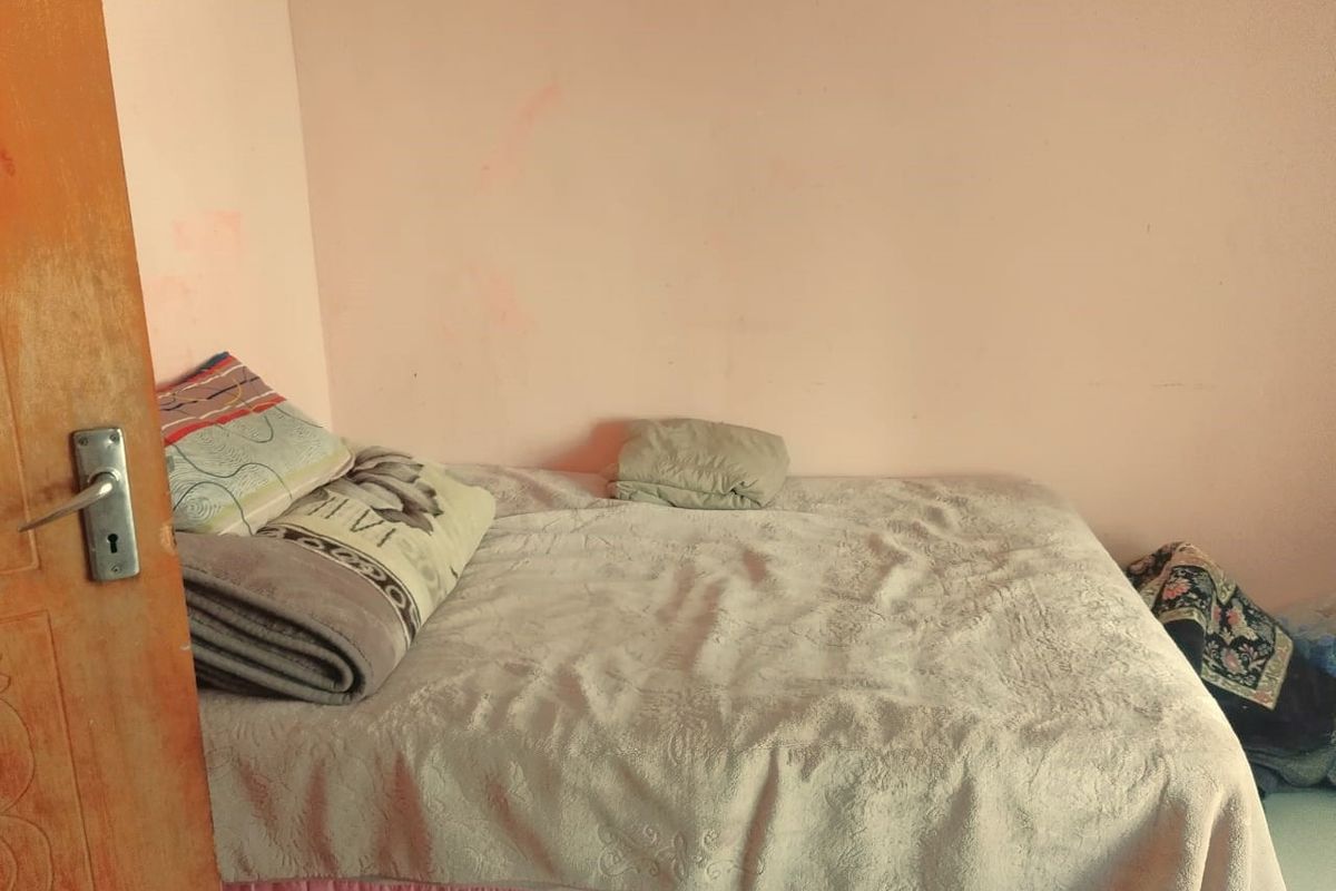 A simple bedroom featuring plain walls and basic interior finishes, suitable for a comfortable sleeping space.