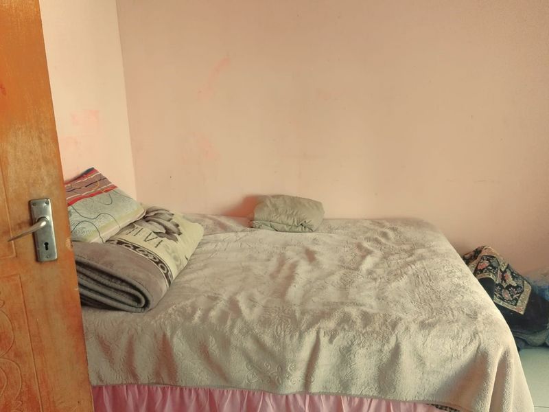 A simple bedroom featuring plain walls and basic interior finishes, suitable for a comfortable sleeping space.
