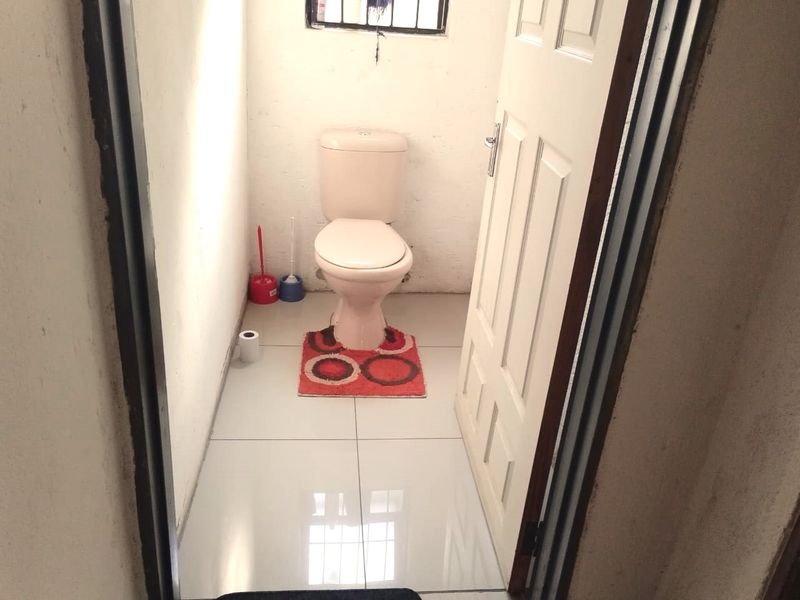 A small, functional bathroom featuring tiled flooring and a standard toilet suite.