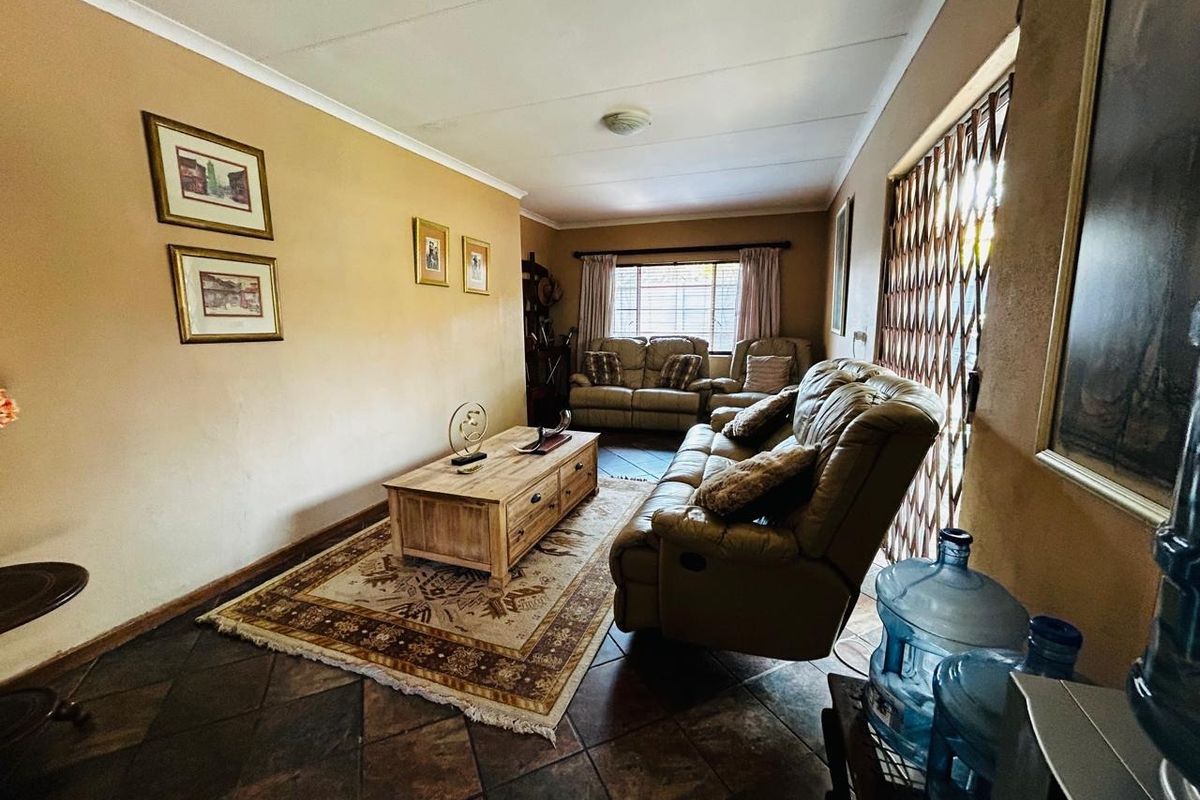A living room featuring tiled flooring, a security gate on the window, and neutral wall finishes.