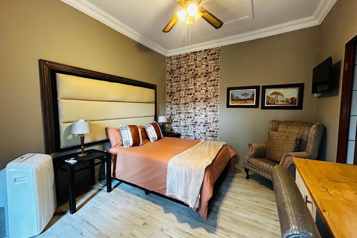 A well-maintained bedroom featuring a decorative brick-style accent wall, crown molding, and a ceiling fan.