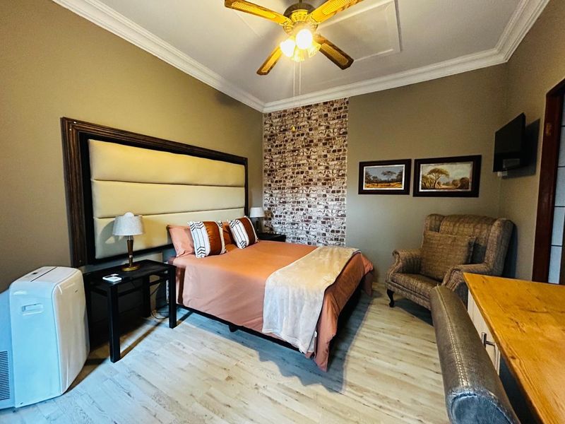 A well-maintained bedroom featuring a decorative brick-style accent wall, crown molding, and a ceiling fan.