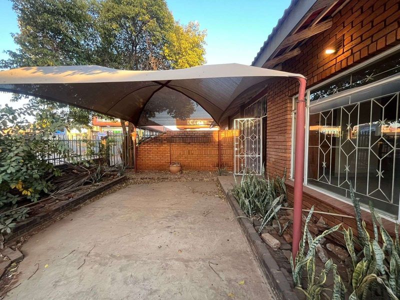 Outdoor patio area featuring a shade sail, brick wall construction, and concrete flooring, providing a functional space for outdoor relaxation.