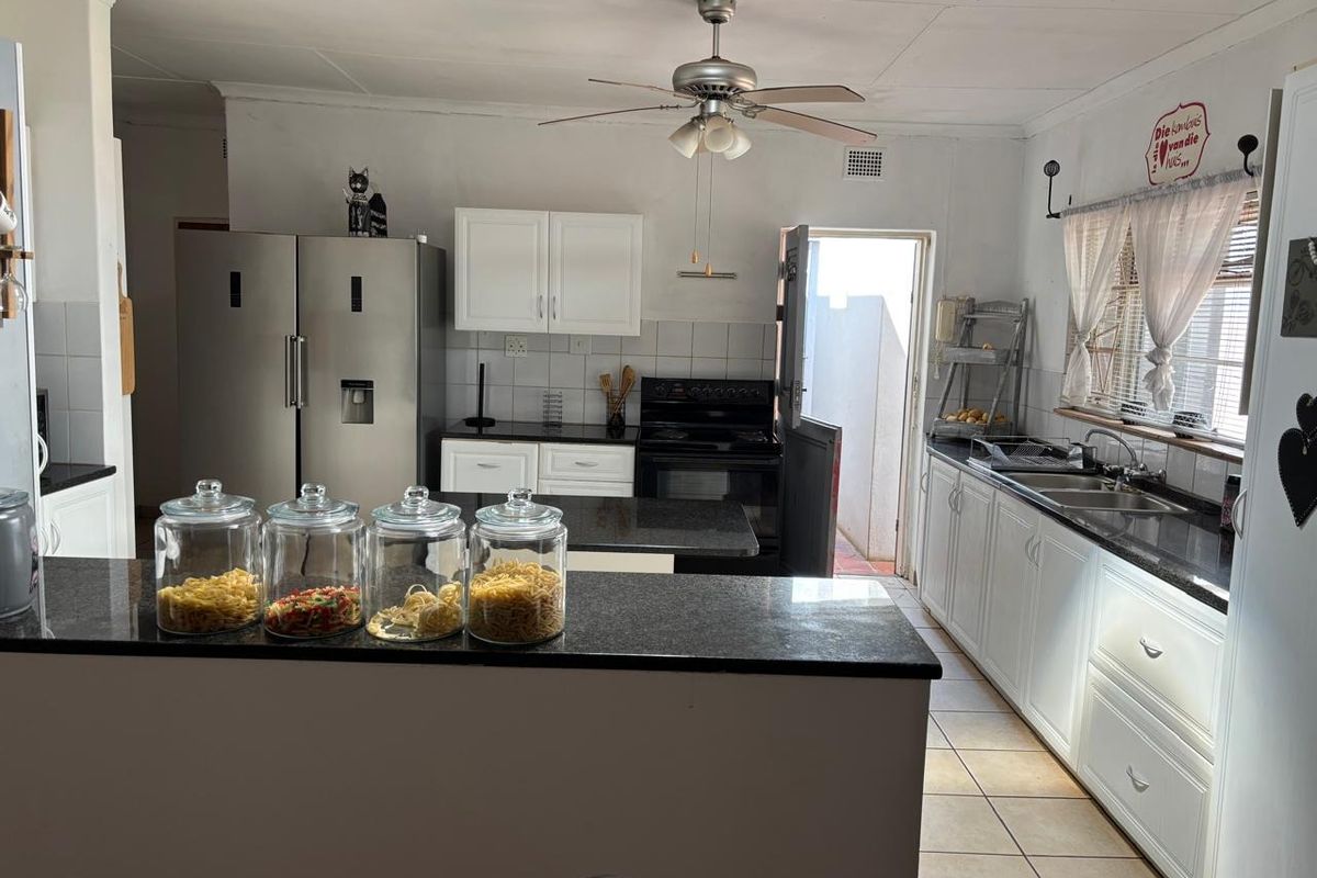 Functional kitchen featuring granite countertops, white cabinetry, a double sink, and a built-in stove, with direct access to the exterior.