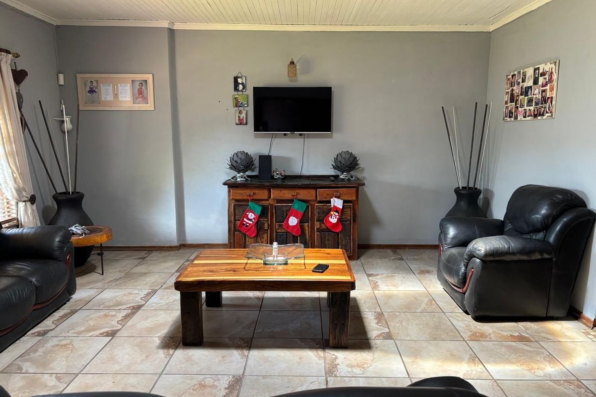 A living room featuring tiled flooring and a painted timber ceiling, providing a functional and comfortable space for relaxation.