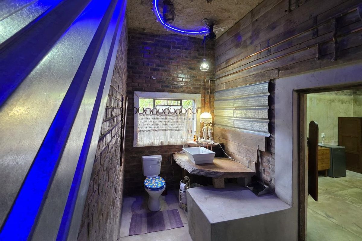 A rustic-style bathroom featuring exposed brick walls, a concrete vanity, and industrial-style lighting elements.