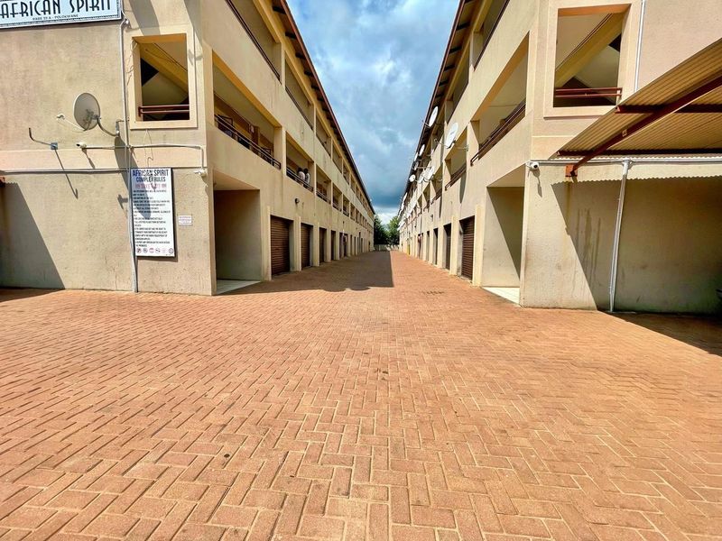 Exterior view of a multi-level townhouse complex featuring a paved driveway, communal walkways, and residential units with exterior access.