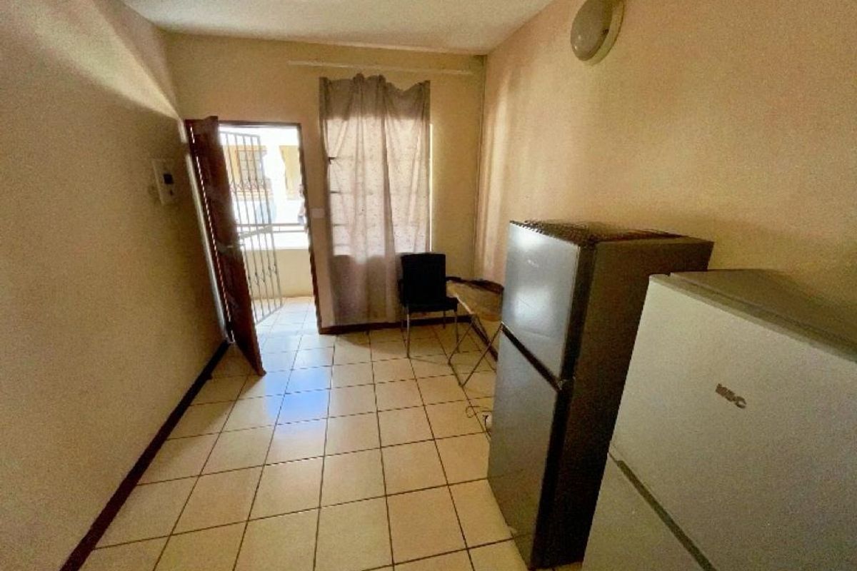 A compact kitchen area featuring tiled flooring and direct access to an exterior space via a security gate.