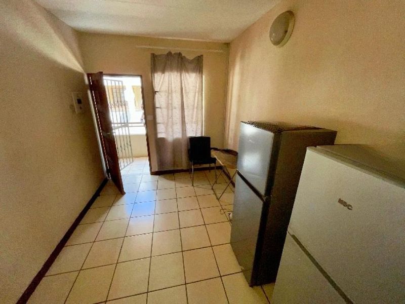 A compact kitchen area featuring tiled flooring and direct access to an exterior space via a security gate.