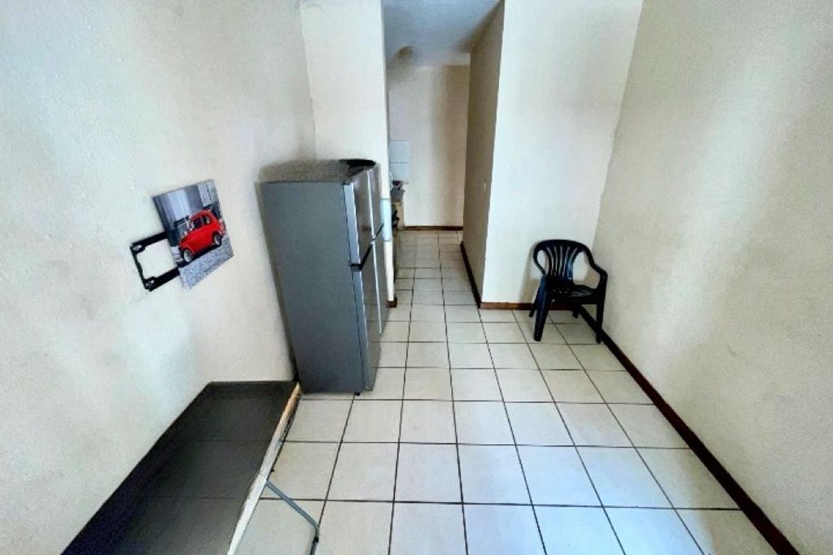 A sparse kitchen area featuring tiled flooring and basic built-in cabinetry, currently vacant and awaiting renovation or modernization.