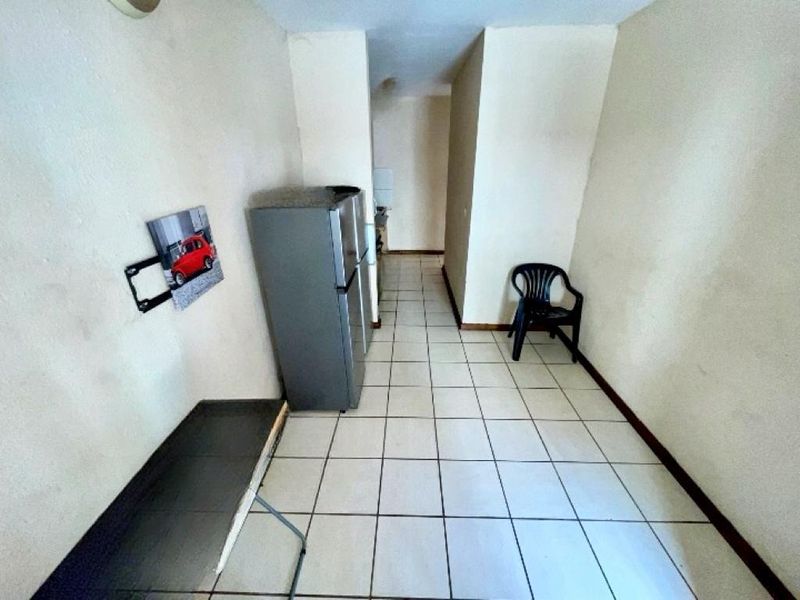 A sparse kitchen area featuring tiled flooring and basic built-in cabinetry, currently vacant and awaiting renovation or modernization.