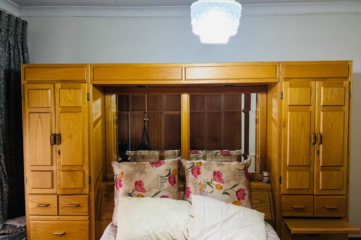 Bedroom featuring extensive built-in wooden cabinetry with integrated mirrored headboard and overhead storage, providing ample storage space.