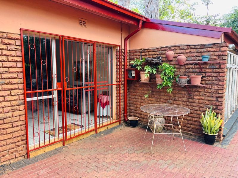 A paved outdoor patio area featuring exposed brick walls, a metal security gate, and sliding glass door access to the interior living space.