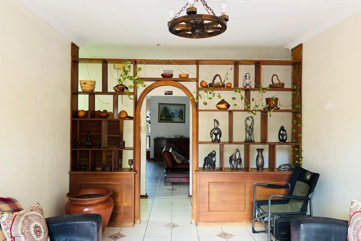 Living room featuring a prominent built-in wooden room divider with an arched opening, tiled flooring, and a rustic wagon wheel chandelier.