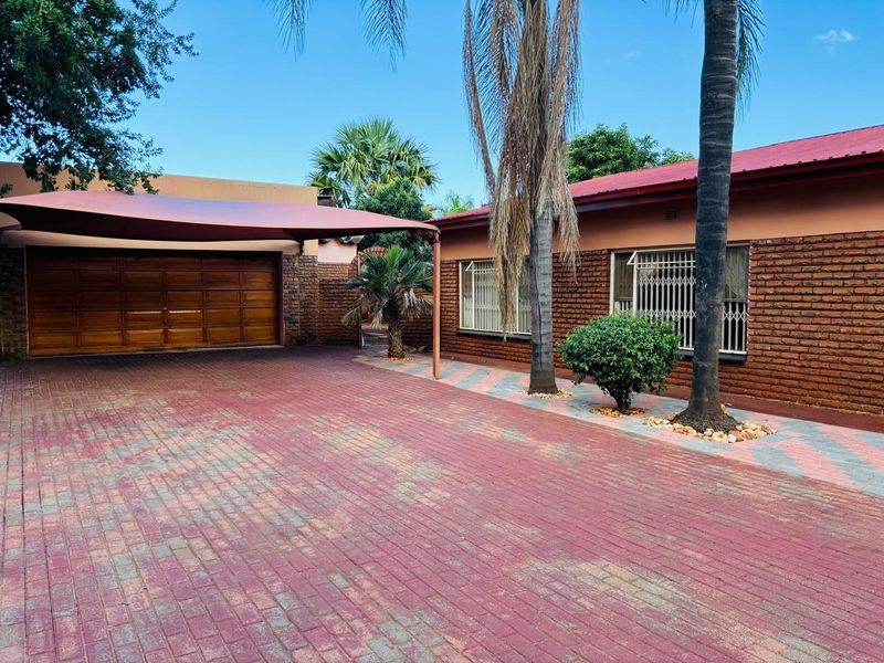 Front exterior view of the house featuring a paved driveway, brick facade, and a covered carport area.