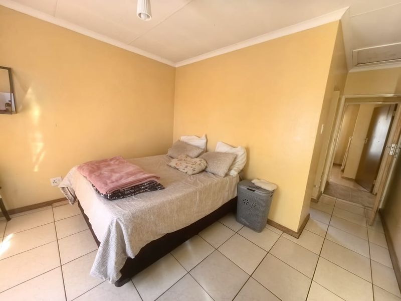 A bedroom featuring tiled flooring and coved ceilings, requiring cosmetic updates to the wall finishes to improve the overall aesthetic.