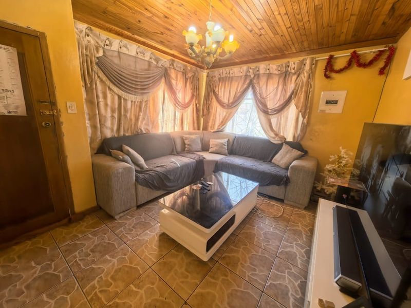 A living room featuring ceramic floor tiles and a timber tongue and groove ceiling, providing a dated aesthetic that could benefit from modernization.