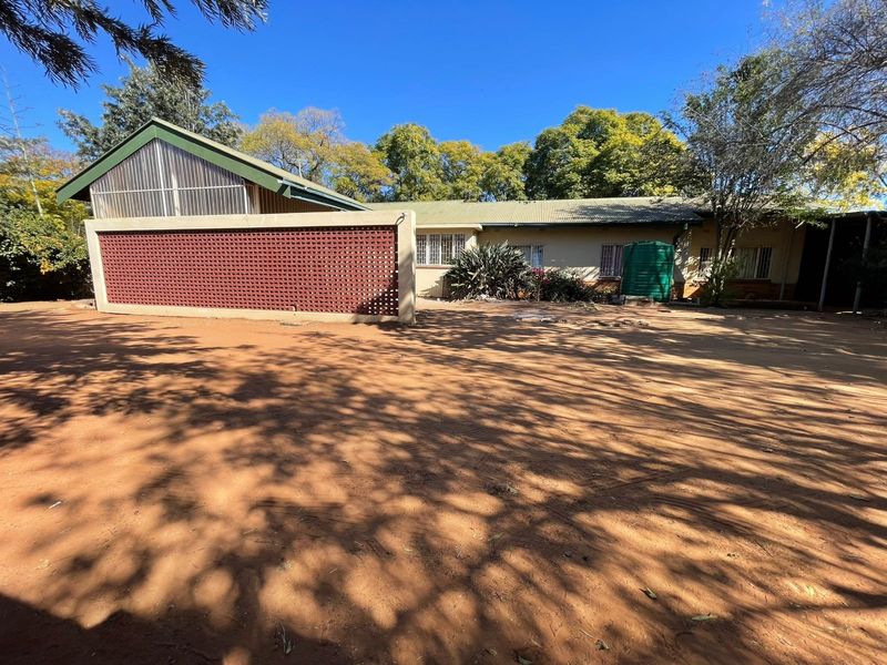 Rear view of the property featuring a large unpaved yard, a decorative breeze block wall, and a water storage tank.