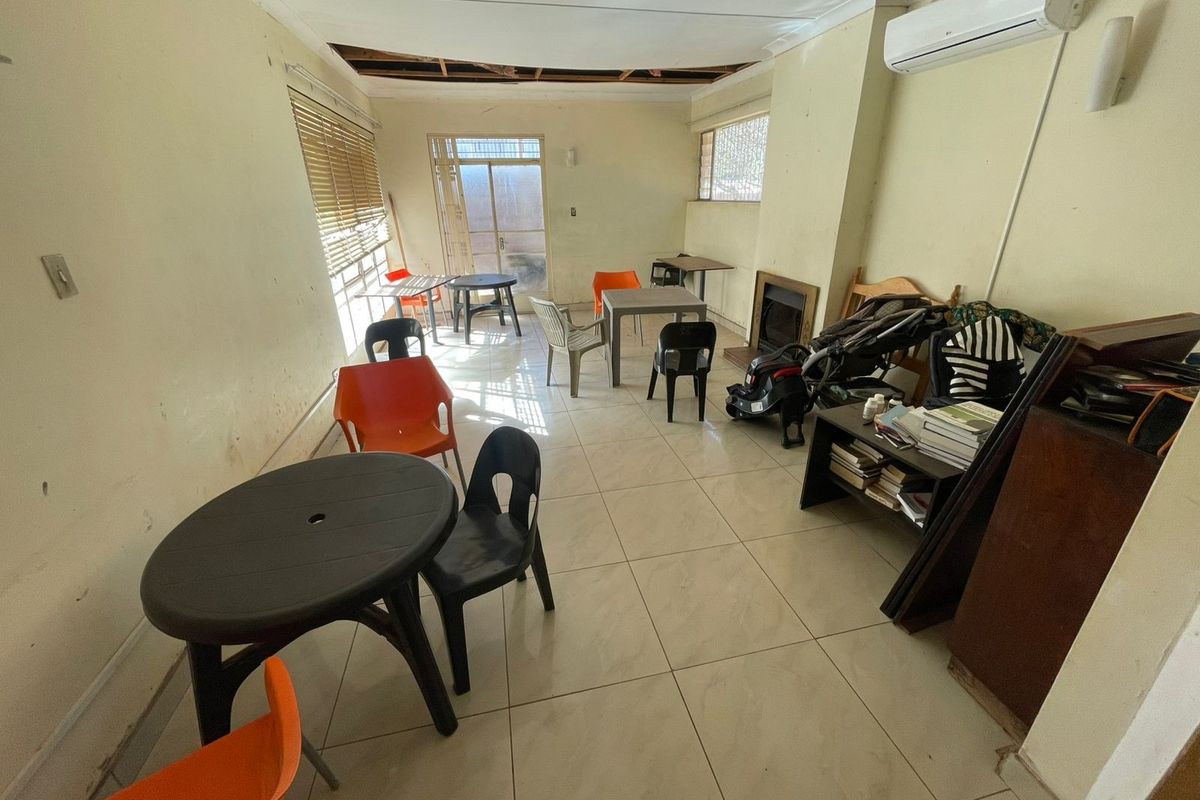 Spacious living area featuring tiled floors, a fireplace, and a split-system air conditioner, currently requiring ceiling repairs and general maintenance.