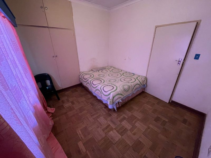 A bedroom featuring original parquet flooring, built-in cupboards, and coved ceilings, requiring cosmetic updates to the wall finishes.
