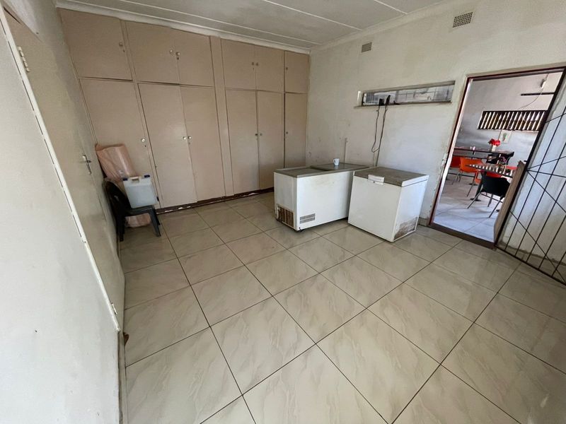 A functional utility space featuring extensive built-in storage cupboards and tiled flooring, offering potential for a pantry, laundry, or storage area.