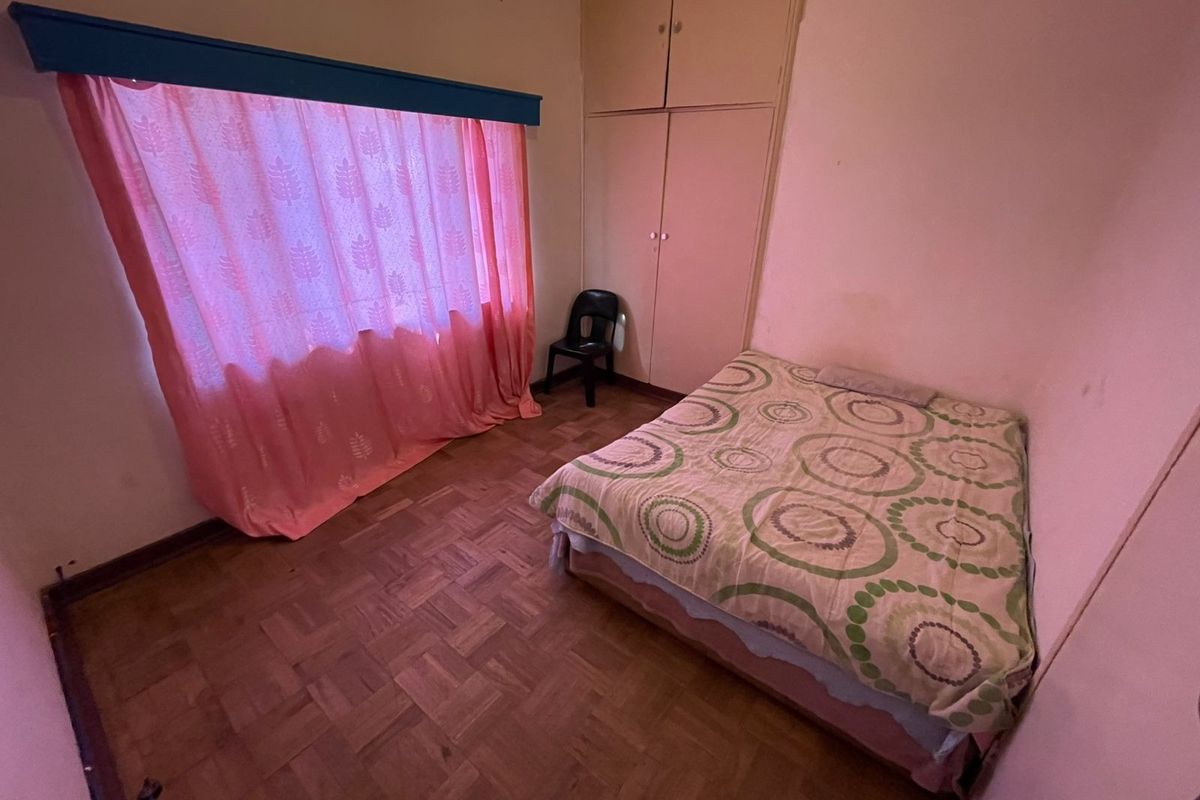 A bedroom featuring parquet flooring and built-in cupboards, requiring cosmetic updates to modernize the space.