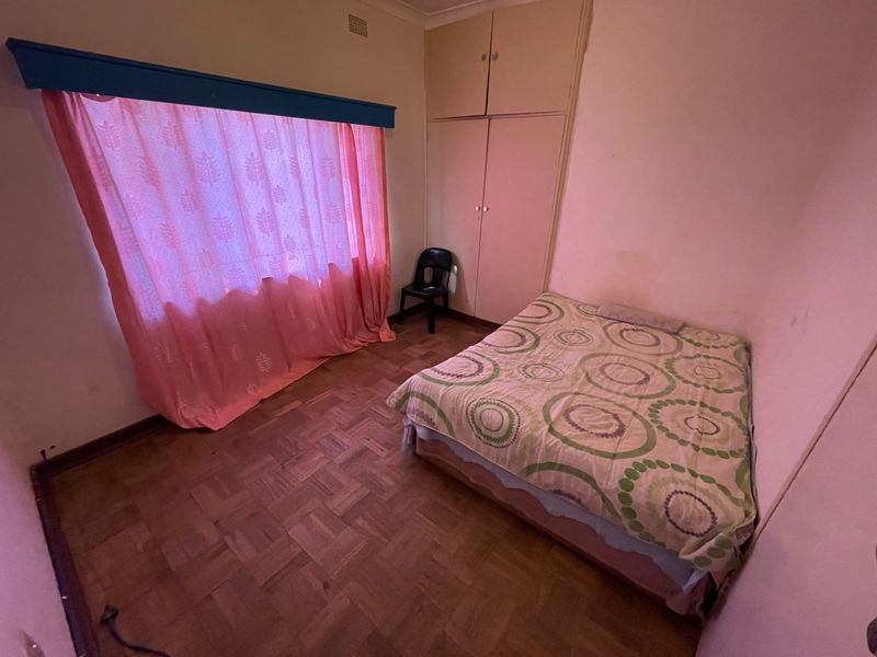 A bedroom featuring parquet flooring and built-in cupboards, requiring cosmetic updates to modernize the space.