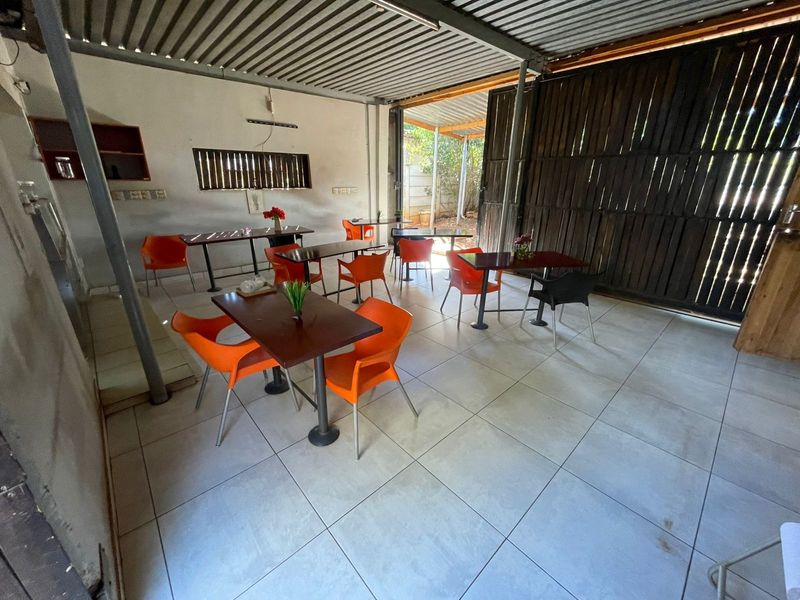 A covered outdoor patio area featuring tiled flooring, exposed steel beams, and timber sliding doors, suitable for an entertainment or dining space.