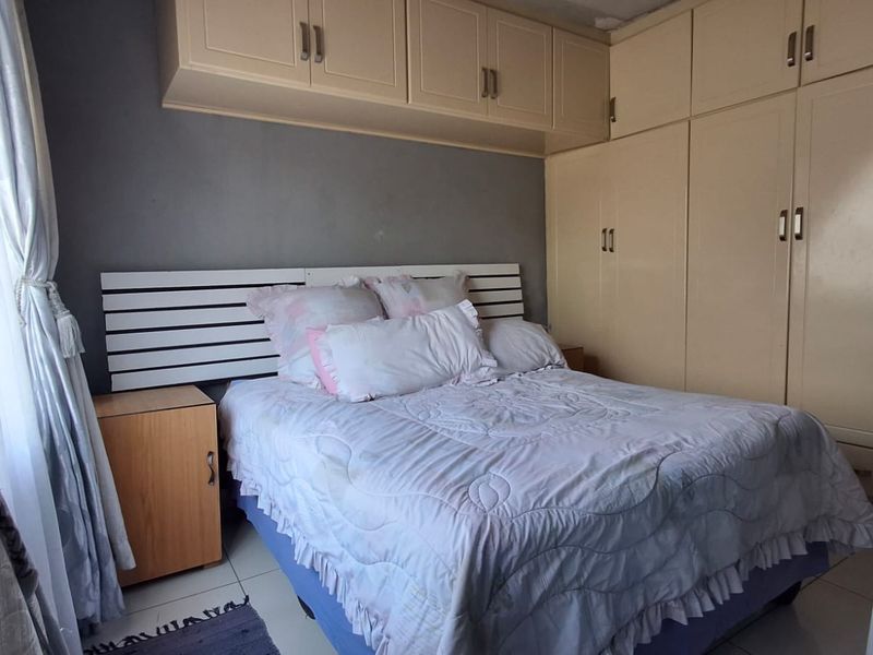 A bedroom featuring built-in cupboards with overhead storage cabinets and tiled flooring.
