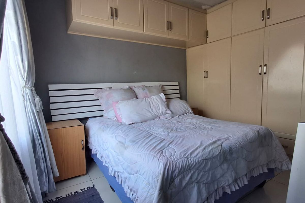 A bedroom featuring built-in cupboards with overhead storage cabinets and tiled flooring.