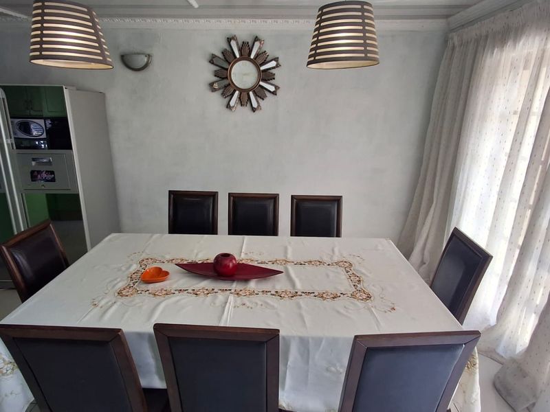A dining room featuring tiled flooring, crown molding, and a wall sconce, providing a functional space for family meals.