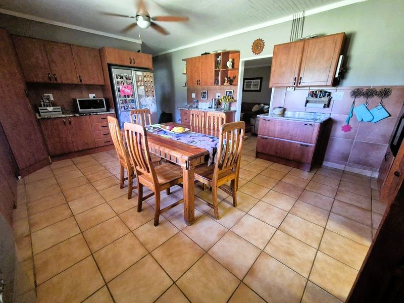 Open plan kitchen and dining area featuring wooden cabinetry, tiled flooring, and a ceiling fan, offering a functional layout for family living.