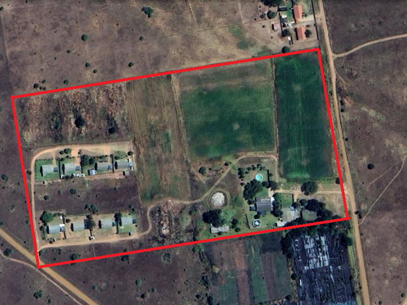 Aerial view of the small holding property showing multiple dwellings, a swimming pool, and expansive land with established access roads.