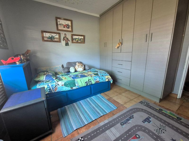 A functional bedroom featuring built-in cupboards and tiled flooring, offering practical storage and a neutral base for personalization.
