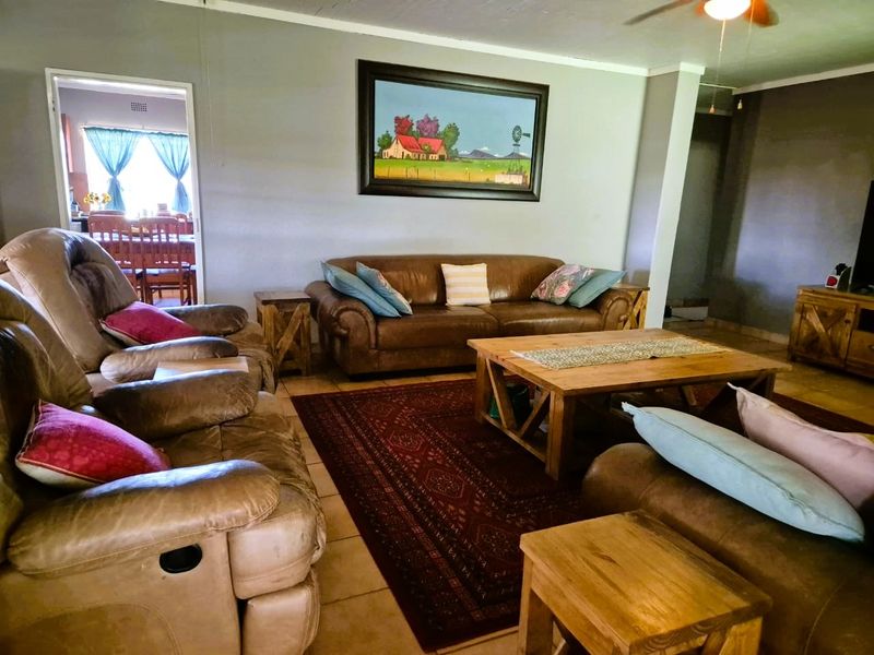 A comfortable living room featuring tiled flooring and a ceiling fan, with an open transition to the adjacent dining area.