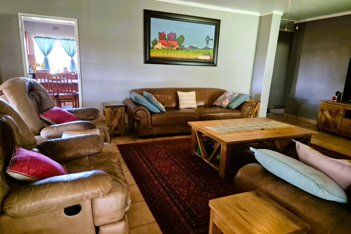 A comfortable living room featuring tiled flooring and a ceiling fan, with an open transition to the adjacent dining area.