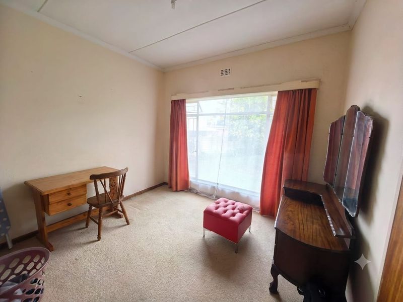 A bedroom featuring a large window, carpeted flooring, and neutral wall finishes, offering a blank canvas for potential renovation and modernization.