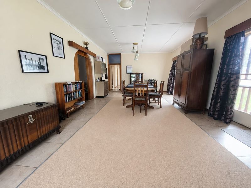 Spacious dining area featuring a combination of tiled and carpeted flooring, an architectural archway, and neutral wall finishes.