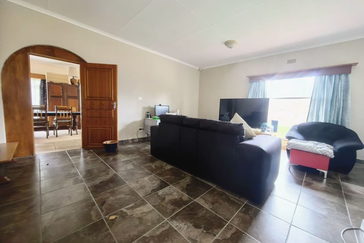 Spacious living room featuring dark tiled flooring and a distinctive arched doorway leading to the adjacent dining area.
