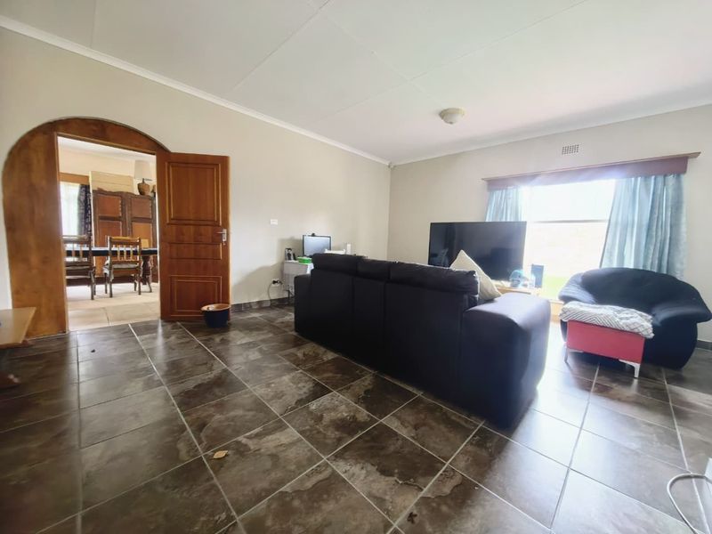 Spacious living room featuring dark tiled flooring and a distinctive arched doorway leading to the adjacent dining area.